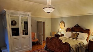 A bedroom with a large bed, a wardrobe, a chandelier, and a red carpet.