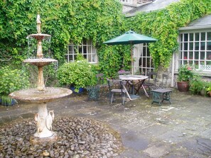 A garden with a fountain, stone patio, and outdoor furniture. - Collon House (Collon)