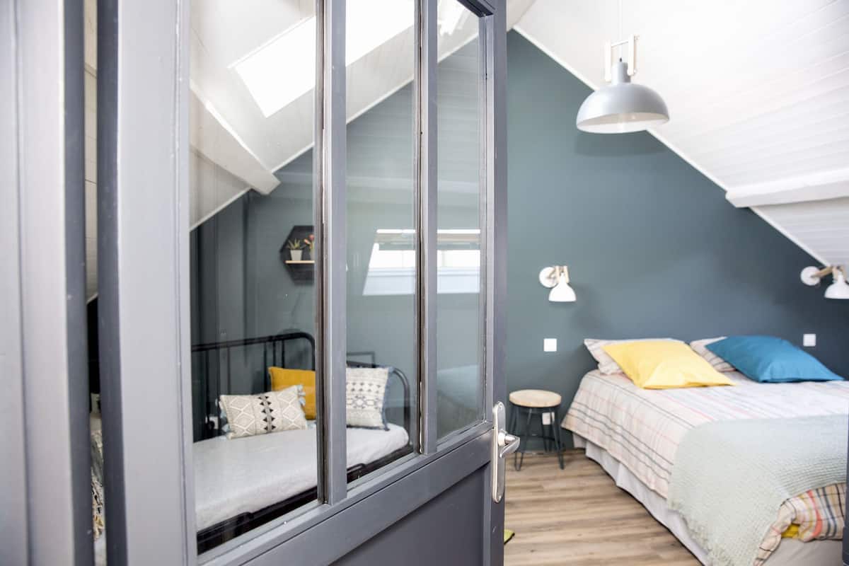 Un dormitorio con cama, mesita de noche y ventana.