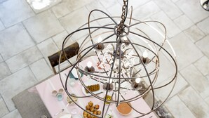 A chandelier with a metal frame and crystal decorations, hanging above a table with various items including plates, cups, and a bowl. - Une Odeur de Tilleul (Montbrison)