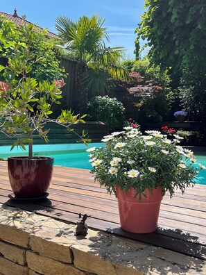 A wooden deck with potted plants and a statue. - Une Odeur de Tilleul (Montbrison)