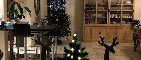 A dining area with a Christmas tree, a cabinet with glass doors, and a dining table with chairs.