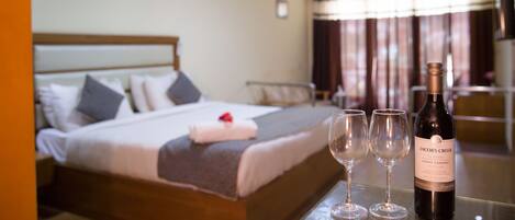 Una camera d'albergo con un letto rifatto, una bottiglia di vino e due bicchieri su un tavolo.