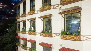 A multi-story hotel with balconies, each with red awnings and potted plants. - Hotel Shobla Royale (Kullu)