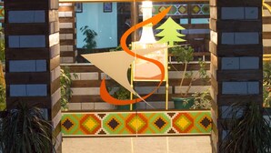 The entrance to Sho'ba Royale with a neon sign, a mosaic tile design, and potted plants. - Hotel Shobla Royale (Kullu)