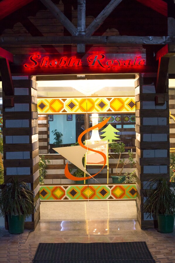 The entrance to Sho'ba Royale with a neon sign, a mosaic tile design, and potted plants. - Hotel Shobla Royale (Kullu)