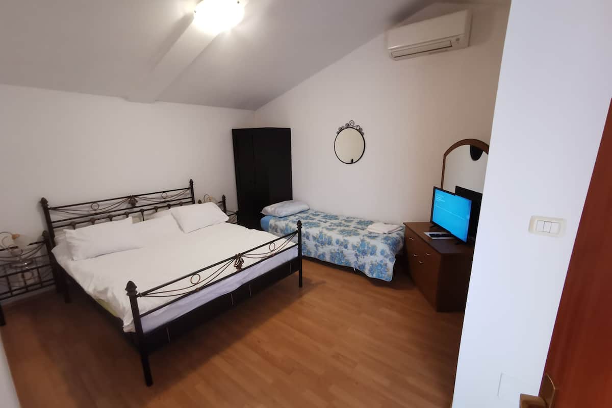 Un dormitorio con una cama, un escritorio con computadora, un armario y un equipo de aire acondicionado.