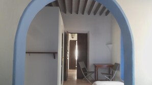 Una habitación con una cama, un escritorio y una silla. Hay una puerta que da a otra habitación.