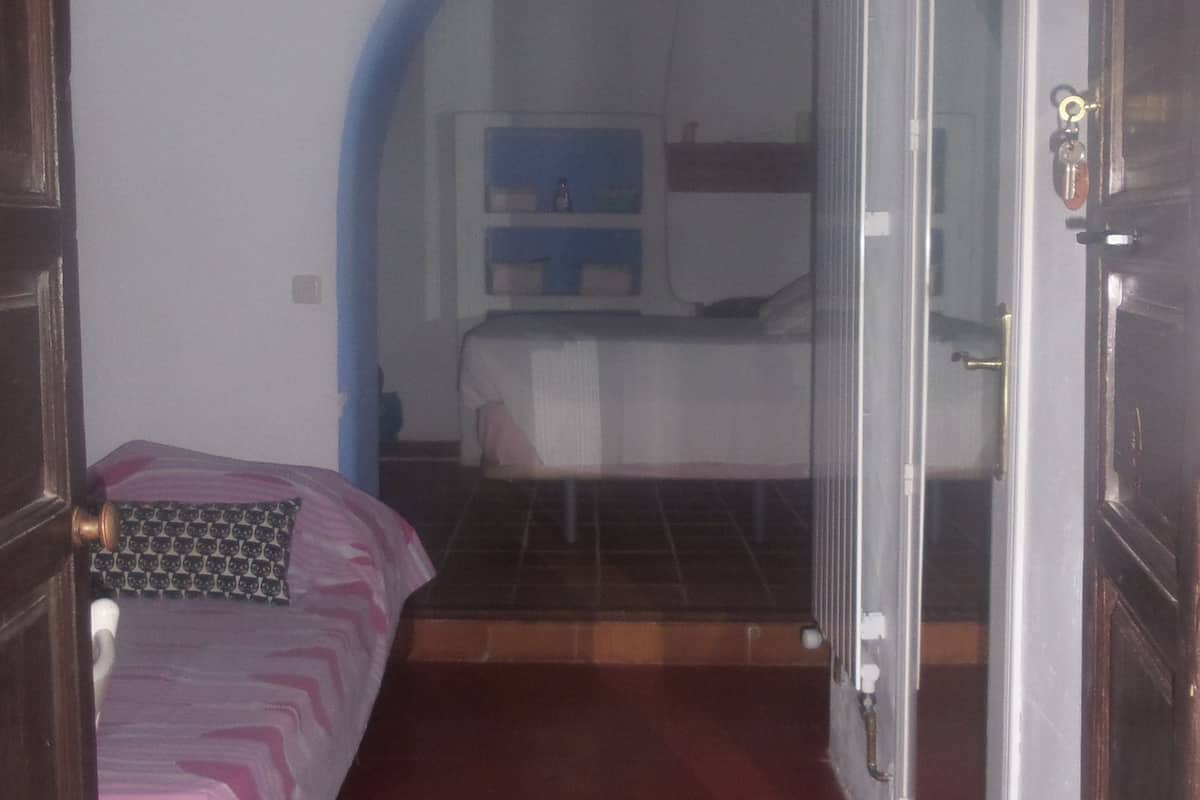 A narrow hallway with a bed on the left and a door on the right.