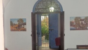 Una habitación con cama, escritorio, silla, ventana y puerta abierta que da a un balcón.