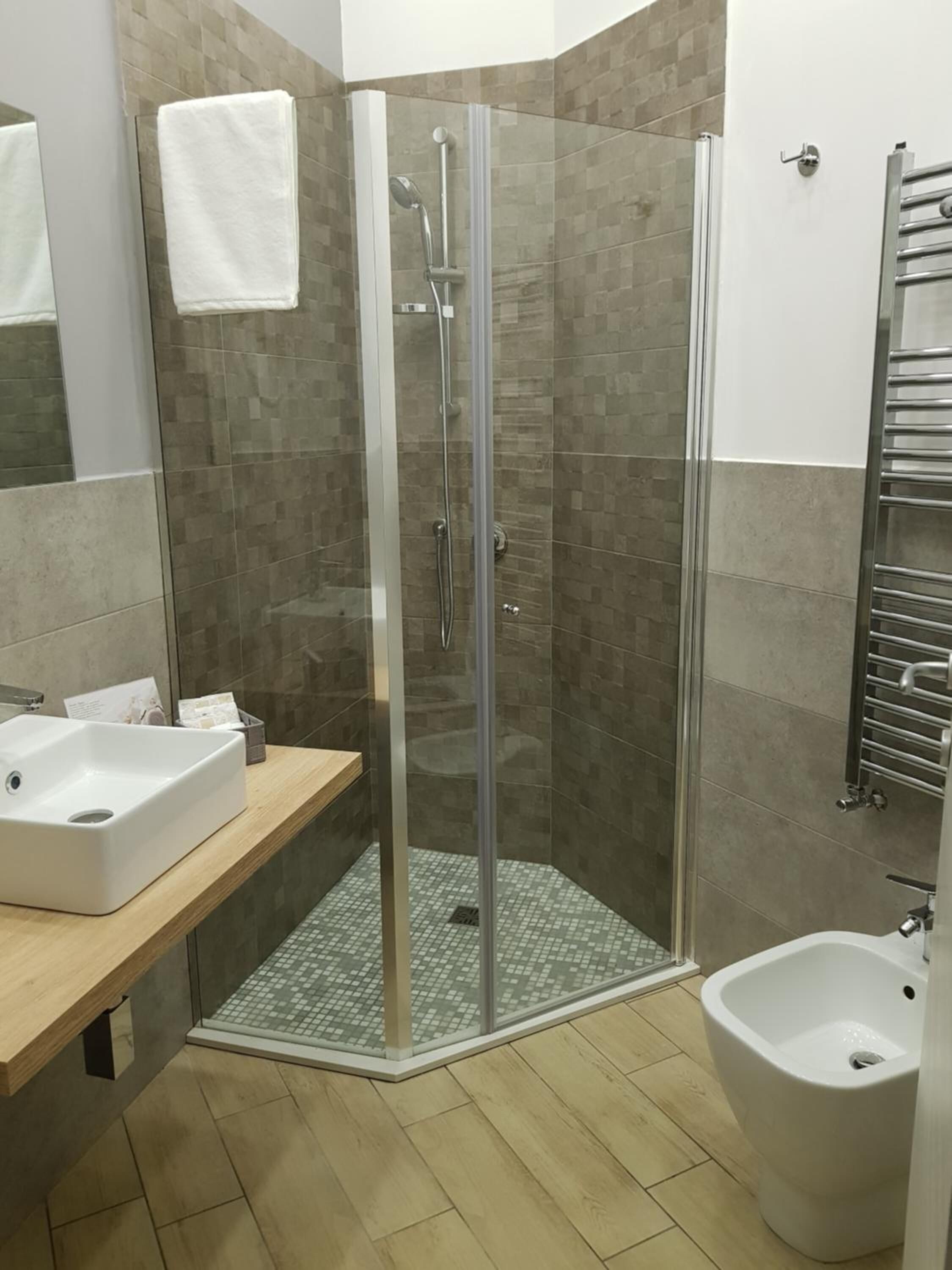 Un bagno moderno con doccia vetrata, lavandino, bidet e portasciuga.