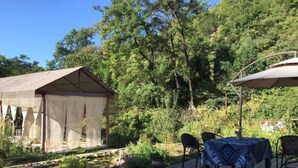 A wooden deck with a table and chairs, surrounded by lush greenery and a small garden. - Banshan Greatwall Mountain View Resort (Huairou)