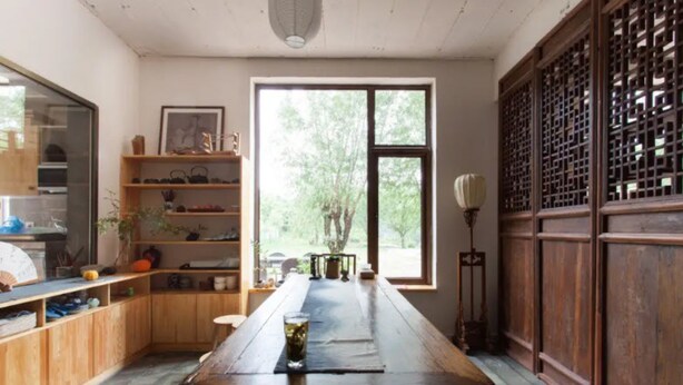 A traditional Japanese-style room with a wooden table, shelves with various items, and a large window providing a view of trees. - Banshan Greatwall Mountain View Resort (Huairou)