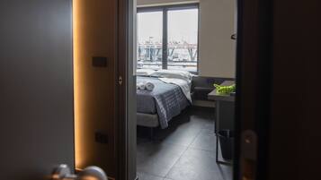 Una camera d'albergo moderna con una grande finestra, un letto, una scrivania e vista sulla città.