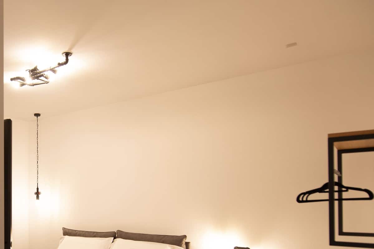 Ett välordnat hotellrum med en säng, ett sängbord och en väggmonterad lampa.