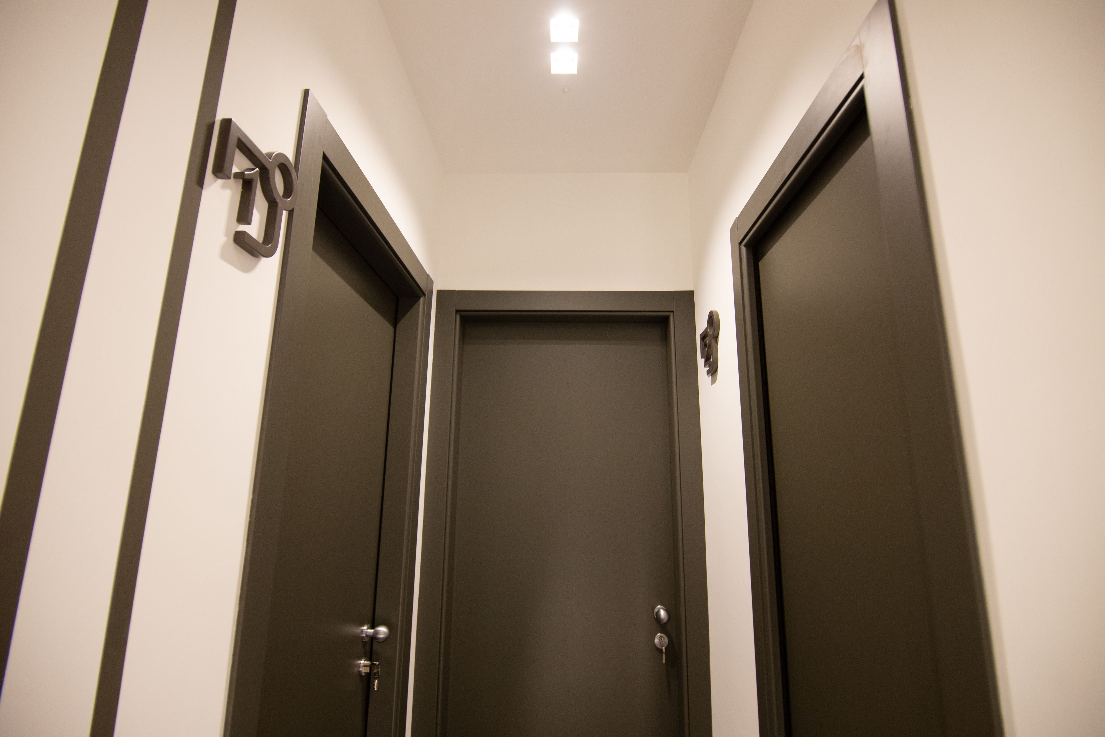 A narrow hallway with two closed doors, one on each side, and a light fixture on the ceiling.