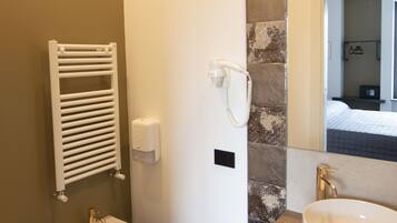 Un baño moderno con bidé, lavamanos y perchero para toallas.