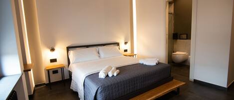 A modern bedroom with a large bed, bedside tables, and a wooden bench.