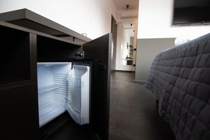 A hotel room with a bed, a built-in refrigerator, and a TV mounted on the wall.