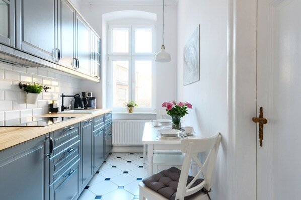 Una cocina moderna con armarios grises, encimera de madera y una mesa de comedor blanca con una silla.