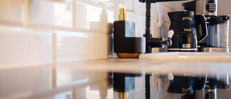 A kitchen with a modern coffee machine, a sink, and a countertop.