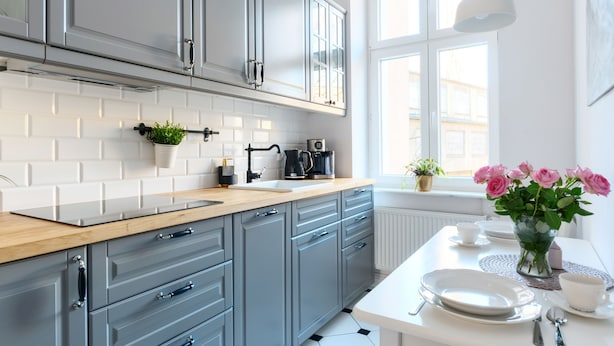 A modern kitchen with grey cabinets, a wooden countertop, and a window providing natural light. -  Apartament Nowe Miasto - Skwer Malarzy (Gorzow Wielkopolski)