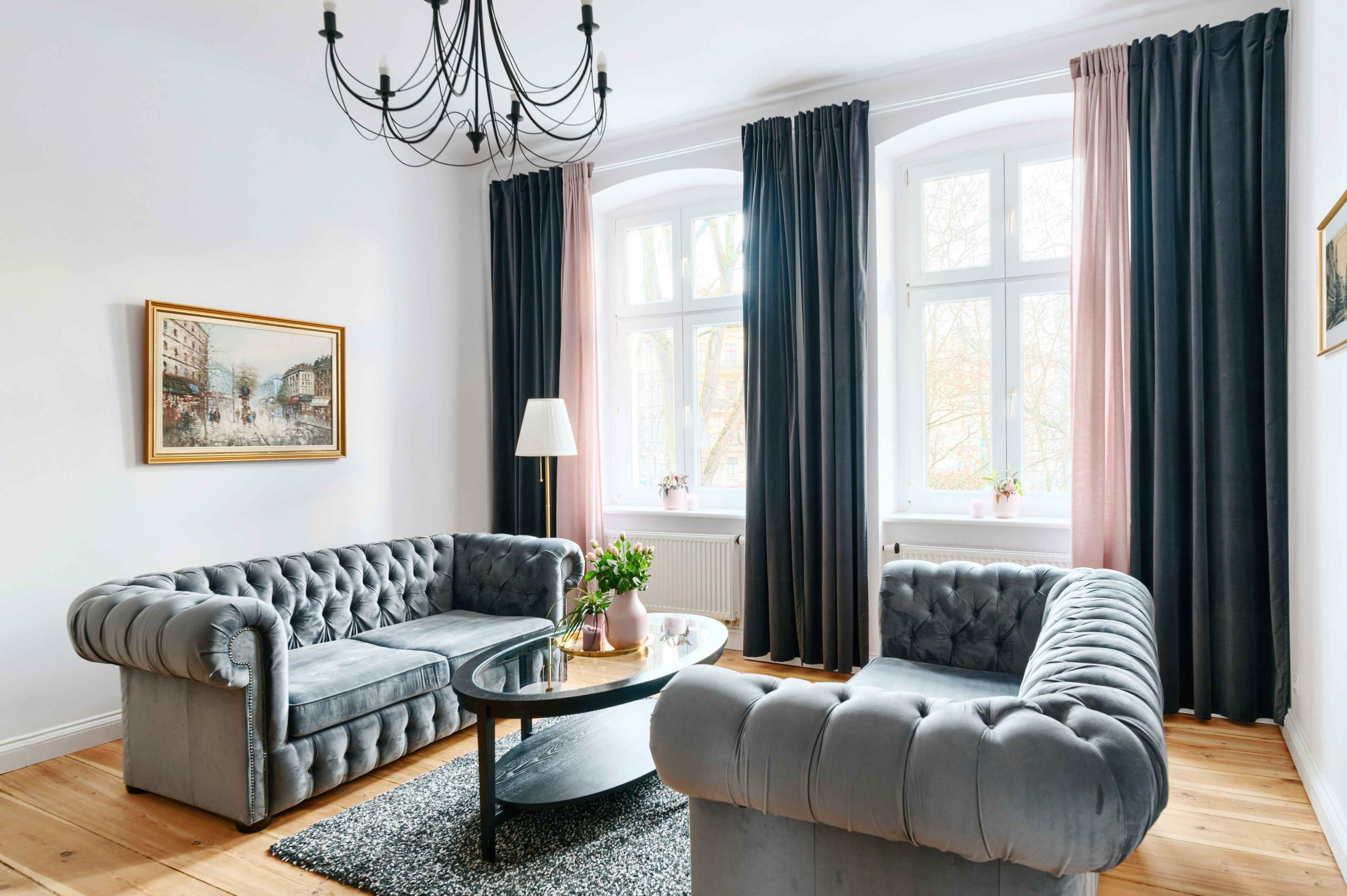 A living room with a grey sofa, a round coffee table, and a chandelier.