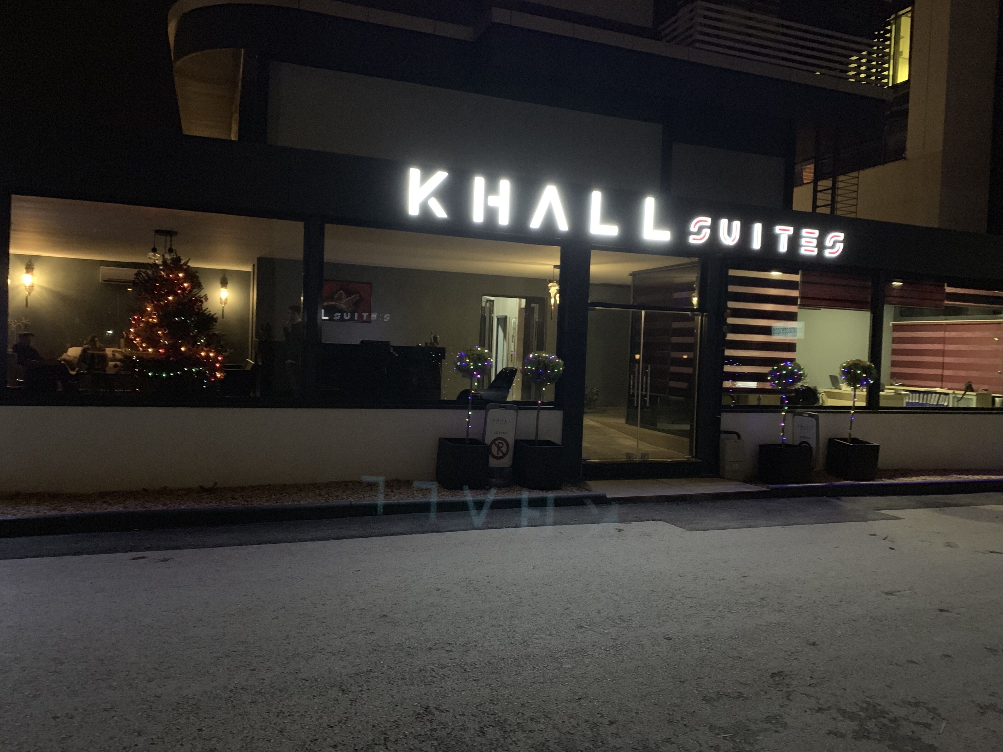 Un hotel llamado "KHALL SUITES" con un árbol de Navidad visible a través de la ventana.