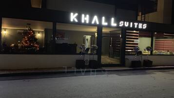 Un hotel llamado "KHALL SUITES" con un árbol de Navidad visible a través de la ventana.