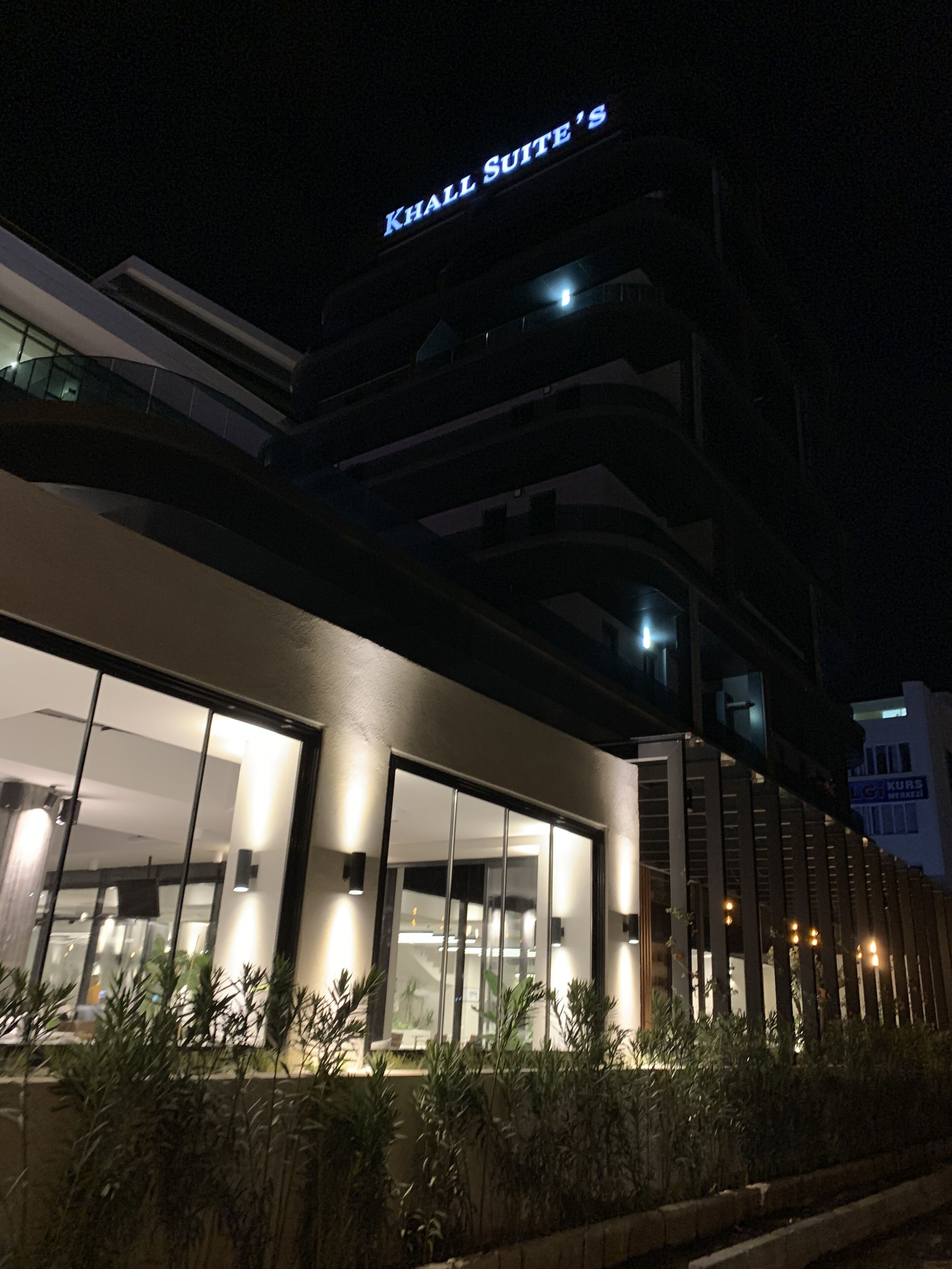 A building with a sign reading "KHALL SUITE'S" at night.