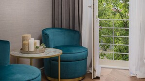 A room with teal upholstered chairs, a small round table with candles and a plant, and a view through a window with curtains. - Five Elements Luxury Rooms (Split)