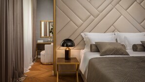 A modern hotel room with a large bed, a nightstand with a lamp, a wooden floor, and a large mirror on the wall. - Five Elements Luxury Rooms (Split)