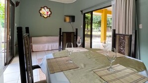 A dining area with a table set for two, a sofa, and a view of the outdoors. -  Las Quintas Casas para Vacacionar (Sardinal)