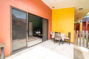 Une terrasse avec une table et des chaises, une porte-fenêtre coulissante et un mur jaune.