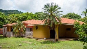 A yellow building with a red roof, surrounded by greenery and a palm tree. -  Las Quintas Casas para Vacacionar (Sardinal)