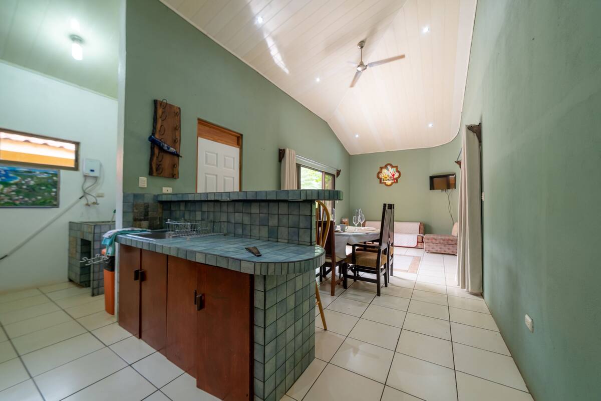 A kitchen with a tiled backsplash, wooden cabinets, and a dining area with a table and chairs.