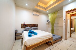 Une chambre avec un lit en bois, une table de chevet, un climatiseur fixé au mur et un rideau vert.