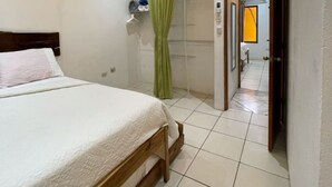 A bedroom with a bed, a green curtain, a white wall, and a ceiling light. -  Las Quintas Casas para Vacacionar (Sardinal)