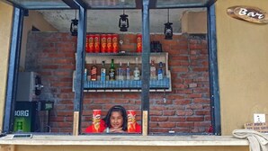 A bar with a brick wall background, shelves with various bottles, and a sign that reads "Bar". - The Lake House (Pokhara)