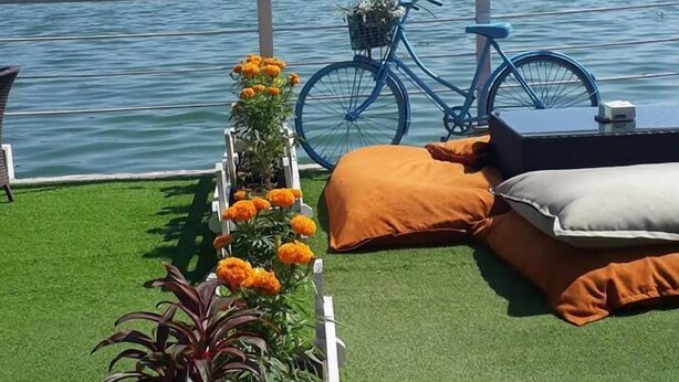 A deck with artificial grass, a bicycle, and a view of a lake with mountains in the background. - The Lake House (Pokhara)