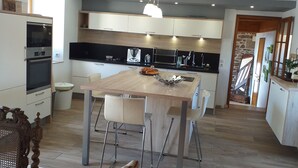 Eine moderne Küche mit einem Holztisch, Barhocker und einem eingebauten Ofen.