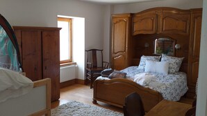 Ein Schlafzimmer mit einem hölzernen Bett, einem Holzschrank, einem Heizkörper, einem Fenster und einem Stuhl.