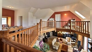 Ein geräumiger Loft mit einer Holztreppe, einer gemütlichen Sitzecke und einem sichtbaren Klavier.