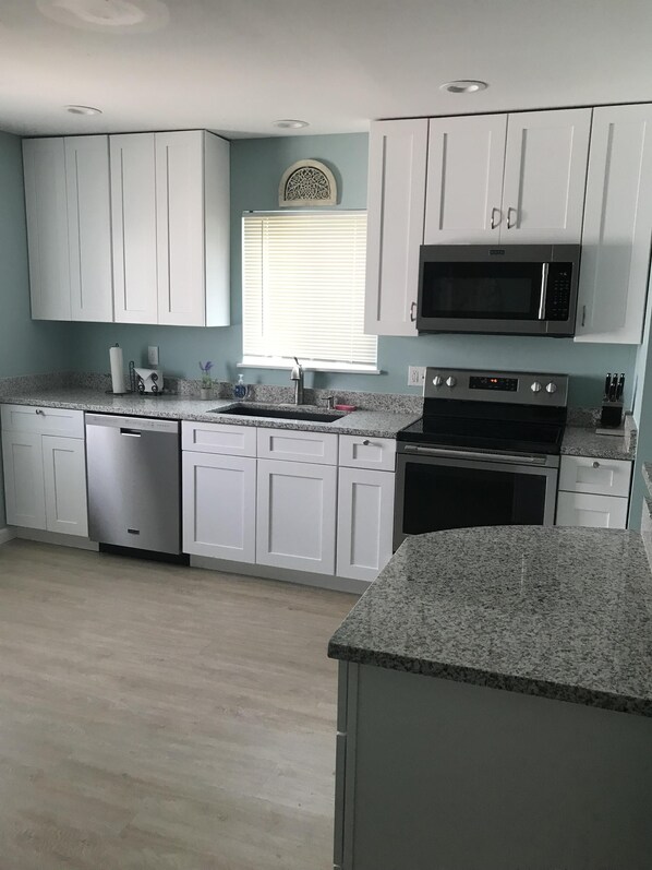 A modern kitchen with white cabinets, a built-in dishwasher, a microwave, and an oven.