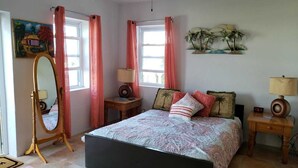 A bedroom with a bed, two bedside tables, a nightstand, a mirror, and a window with curtains. - Paul's Oceanview Apartment with Amazing Sunsets + Twizy Charger (Sandy's)