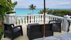 A balcony with wicker furniture and a view of the ocean. - Paul's Oceanview Apartment with Amazing Sunsets + Twizy Charger (Sandy's)