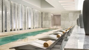 Zona de piscina interior moderna con una larga banca a lo largo de la piscina, cada una con una toalla.