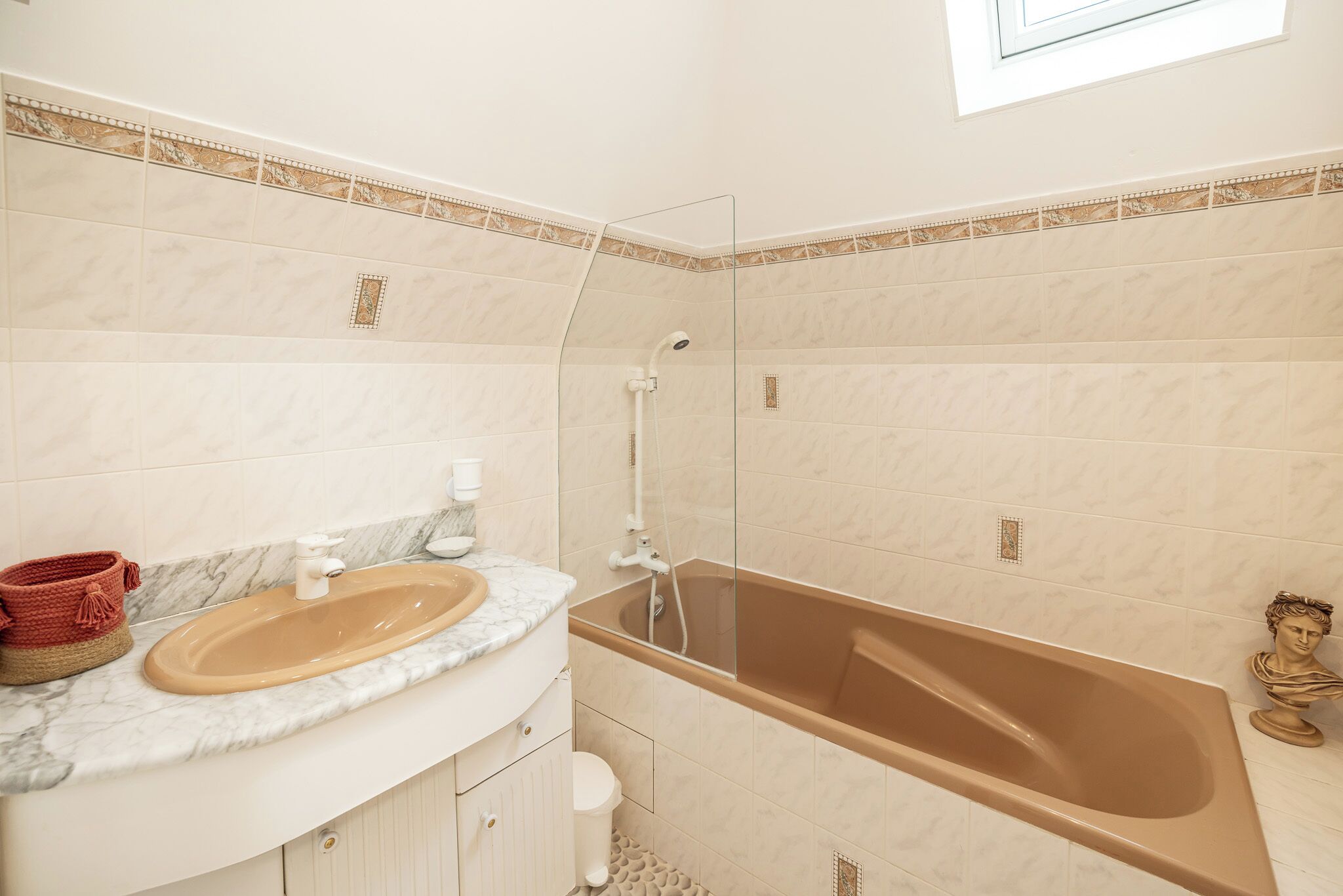 Une salle de bain avec une baignoire, un lavabo et une fenêtre.