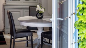 A dining area with a round table, two chairs, a vase with flowers, and a cabinet with glass doors. - Gite La Tour - Cocoon for 2 with pool and nature (Saint-Geyrac)