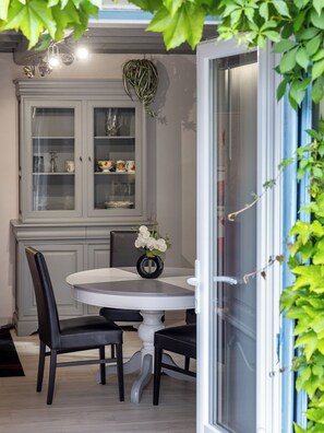 Un coin repas comprenant une table ronde, deux chaises, un vase avec des fleurs et un buffet aux portes vitrées.